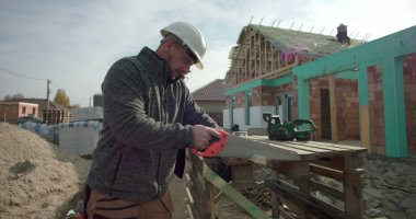 Derme çatma tezgahta odun kesen inşaatçı, arka plandaki bina, göreve odaklanmış, yapım aşamasındaki yapı, iş başında yetenekli işçilik