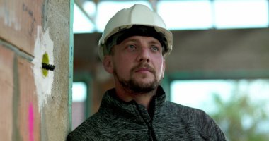 İnşaat işçisi inşaat sahasına özenle bakıyor ahşap çerçeve yapısının arka planı modern inşaattaki odak ve adanmışlığı temsil ediyor.