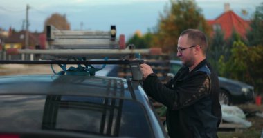 Çalışanlar merdiveni arabanın çatı rafına yerleştiriyor, ulaşıma, açık havaya, inşaat aletlerine, güvenlik ekipmanlarına, yerleşim alanının geçmişine hazırlanıyor.