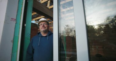 İnşaat projesinde inşaat alanında tecrübeli bir inşaat işçisi çerçevenin altından kendine güveniyor, odak noktasını ve profesyonelliğini gösteriyor.