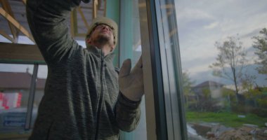 İşçi, konut inşaat sahasında tam hizalama için pencere çerçevesini inceliyor, kalite kontrol denetimi devam ediyor