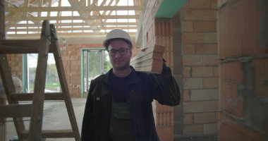 İnşaat işçisi, inşaat alanındaki dar koridorlarda, tamamlanmamış konut binasının içinde ahşap kalaslar taşıyan, inşaat işçisi.