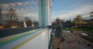 İnşaat duvarına karşı mezura tutan işçiler, inşaat, açık hava projesi, takım çalışması, hassasiyet çalışması, bina kurulumu için ölçümleri ayarlıyorlar.