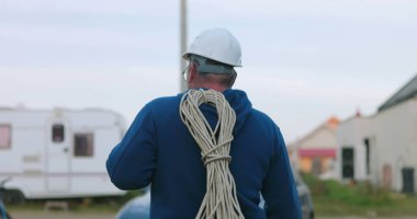 Dışarıdaki çalışma alanına yakın bir yerde kabloyla yürüyen işçiler, elektrik işi için hazırlanıyor ve verimli inşaat projesinin yürütülmesi için araçları düzenliyor