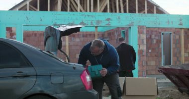 İnşaat alanındaki araç bagajından araç gereç boşaltma, açık hava yenileme projesi için ekipman hazırlama, verimli görev organizasyonuna odaklanma