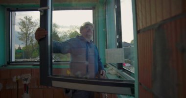 Konut inşaatı projesinde pencere kurulumunu doğrulayan inşaat işçisi, hizalama ve sığdırmaya odaklandı