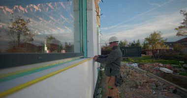 İnşaat duvarı boyunca mezurayı dikkatlice hizalayan işçiler, inşaat doğruluğu, odaklanmış ifade, tesis kurulumu ve kurulum süreci için ölçümler alıyor