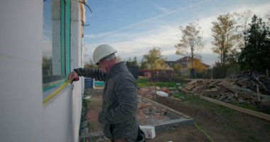 İnşaat duvarına karşı mezura tutan işçiler, inşaat, açık hava projesi, takım çalışması, hassasiyet çalışması, bina kurulumu için ölçümleri ayarlıyorlar.