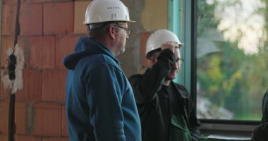 İnşaat işçileri pencere kenarından sohbete daldılar, proje detayları, başlıklar, iç yenileme, ciddi takım çalışması atmosferi, işbirliği çabaları