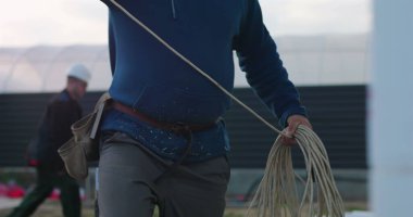 İnşaat alanında büyük miktarda kablo düzenleyen, araçları tutan ve yöneten, açık hava çalışma ortamında elektrik kurulumuna hazırlanan işçiler