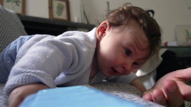 Bebek kanepeye uzanmış neşeli bir ifadeyle, dinleniyor ve gülümsüyor, neşeli ve mutlu bir bebek, annesiyle birlikte evde, aile içinde, dünyayı rahatça keşfeden bir bebek.