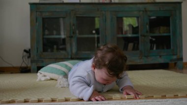 Bebek paspasın üzerinde yatıyor, elleriyle dokunmuş ve keşfetmiş, sakin bir ev ortamında dokunsal bağlılık ve duyusal gelişime odaklanmış.