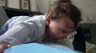 Bebek kanepeye uzanmış neşeli bir ifadeyle, dinleniyor ve gülümsüyor, neşeli ve mutlu bir bebek, annesiyle birlikte evde, aile içinde, dünyayı rahatça keşfeden bir bebek.