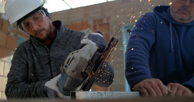 Açı öğütücüyle metal kesen işçiler, bitmemiş bina, takım çalışması ve işçiliğinde çalışan iki adam gibi kıvılcımlar uçuşuyor.