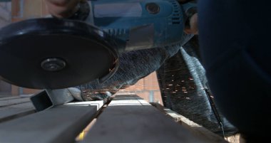 Açı öğütücüsünün metali, kıvılcımları ve tozu keserken düşük açılı görüntüsü, işçilerin el ele tutuşması aracı, hassasiyet ve kontrol üzerine odaklanma, 800 fps yavaş çekim.