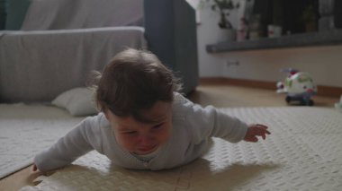 Bebek paspasın üzerine düşüyor, kafaya vurduktan sonra ağlamaya başlıyor, yumuşak yüzeyle korunuyor, güvenli bir ev ortamında erken gelişimi ve duygusal tepkiyi gösteriyor.