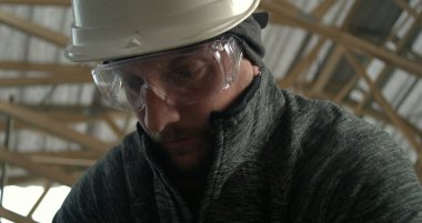 Başlık ve gözlüklü inşaat işçilerinin yakın çekimleri, sanayi görevine yoğun bir şekilde odaklanma, güvenlik donanımı ve inşaat alanındaki hassasiyet