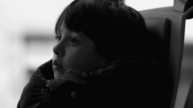 Otobüs koltuğunda oturan genç bir çocuğun yakın plan profili, siyah ve beyaz, derin düşüncelere dalmış, düşünceli bir ifade, kapalı alanda ulaşım, hareket halindeyken düşüncelere dalmış.