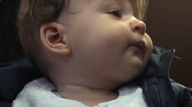 Bebeğe kardeş tarafından dokunuluyor, yumuşak bir gülümseme, hassas bir an, günlük aile içi etkileşim, rahat kışlık giysiler giyme, beslenme ve bağlanma deneyimi, yakın görüş