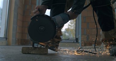 Beton blokta açı öğütücü kullanan işçiler, endüstriyel inşaat işinde kıvılcımlar uçuşuyor, hassas iş yapıyorlar ve süper yavaş çekimde odaklanıyorlar..