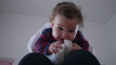 Bebek, anne kucağında otururken çorapla oynuyor, tutuyor ve ısırıyor. Ev ortamında meraklı ve eğlenceli etkileşimler, merak uyandıran dokuları keşfediyor..