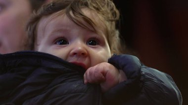 Bebek ceketi, yukarı bakıyor, kışlık palto giyiyor, sıcak aile manzarası, meraklı ve düşünceli ifade, sıcaklık ve koruma, günlük iç mekan sahnesi