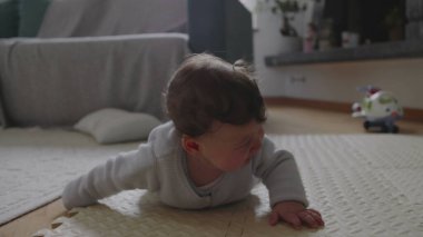 Bebek paspasın üzerine düşüyor, kafaya vurduktan sonra ağlamaya başlıyor, yumuşak yüzeyle korunuyor, güvenli bir ev ortamında erken gelişimi ve duygusal tepkiyi gösteriyor.