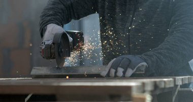 Açı öğütücüsüne yakın çekim. 800 fps hızla hareket eden kıvılcımlarla metali kesiyor. Eldivenli işçiler ellerini sabit tutuyor, hassasiyet ve güvenliğe odaklanıyor..