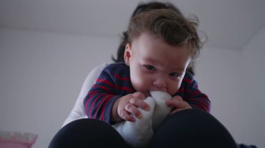 Bebek, anne kucağında otururken çorapla oynuyor, tutuyor ve ısırıyor. Ev ortamında meraklı ve eğlenceli etkileşimler, merak uyandıran dokuları keşfediyor..