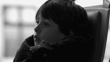 Otobüs koltuğunda oturan genç bir çocuğun yakın plan profili, siyah ve beyaz, derin düşüncelere dalmış, düşünceli bir ifade, kapalı alanda ulaşım, hareket halindeyken düşüncelere dalmış.