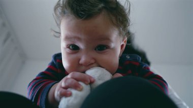 Anne kucağında otururken bebek ısıran çorabın yakın çekimi, neşeli ve meraklı bebek dokuyu keşfediyor, aile evinde samimi ve şefkatli bir an..