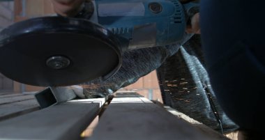 Açı öğütücüsünün metali, kıvılcımları ve tozu keserken düşük açılı görüntüsü, işçilerin el ele tutuşması aracı, hassasiyet ve kontrol üzerine odaklanma, 800 fps yavaş çekim.
