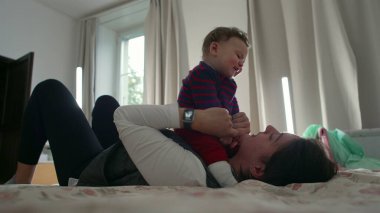 Anne yatakta yatarken bebeği kaldırıyor, oyun oynuyor ve aile evinde kaynaşıyor, birlikte eğleniyor, sevgi ve sevgi dolu bir bağ kuruyor.