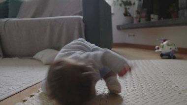 Bebek paspasın üzerine düşüyor, kafaya vurduktan sonra ağlamaya başlıyor, yumuşak yüzeyle korunuyor, güvenli bir ev ortamında erken gelişimi ve duygusal tepkiyi gösteriyor.