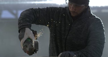 Açı öğütücüyle metal öğüten, 800 fps 'te yavaş çekimde kıvılcım saçan, odaklanmış ifade, güvenlik gözlüğü takan, detaylı endüstriyel ayarlar