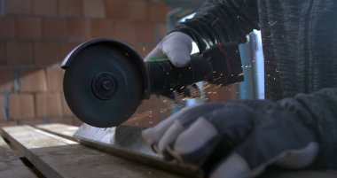 Açı öğütücü, kıvılcımlar saçan metali kesiyor, zanaatkarlar eldiveni yerinde tutuyor, güvenlik ve beceriye odaklanıyor, atölye ayarları, 800 fp yavaş çekim.