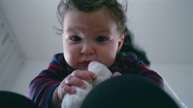 Anne kucağında otururken bebek ısıran çorabın yakın çekimi, neşeli ve meraklı bebek dokuyu keşfediyor, aile evinde samimi ve şefkatli bir an..