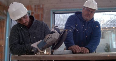 İki işçi, inşaat sahasında metal, odaklanmış ve hassas, kıvılcımlar uçuşuyor, takım çalışması ve endüstriyel güvenlik kullanıyor, 800 fp yavaş çekim