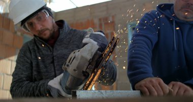 Açı öğütücüyle metal kesen işçiler, bitmemiş bina, takım çalışması ve işçiliğinde çalışan iki adam gibi kıvılcımlar uçuşuyor.
