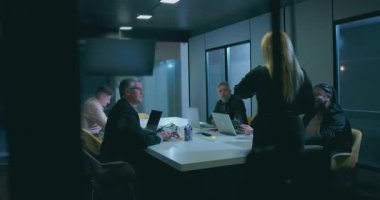 Modern kurumsal ofiste akşam iş toplantılarında yönetim kurulu başkanı olan kadın yönetici çeşitli takımlara liderlik ediyor.