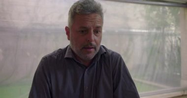 Terapi seansında içsel acı ve duygusal gerilimi ifade eden bir adam grup güven ve iyileşme çemberi içinde dikkatle dinlerken...