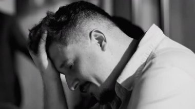 Acı dolu bir ifadeyle el ele tutuşan genç adam evde tek başına otururken duygusal çöküntü ya da ruhsal çöküntü yaşıyor.