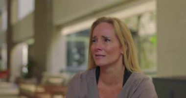 Grup terapisi sırasında duygularıyla konuşan bir kadın derin üzüntü ve hassasiyetini dile getirirken aynı zamanda iyileştirici uzayda destekleyici akranlarıyla iletişim kuruyor.