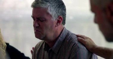 Bir erkek terapi seansı sırasında duygu yoluyla konuşmaya çalışırken diğer bir üye de kırılganlık ve bağlantı anında omuz omuza destek veriyor.