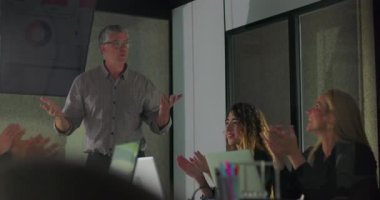 Erkek sunucu, modern konferans odasında ofis takımı toplantısında başarılı bir şekilde sunulduktan sonra motivasyon enerjisiyle gülümsüyor ve alkışları cesaretlendiriyor.