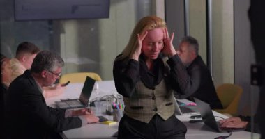 Ofis toplantısı sırasında gergin bir ifadeyle el ele tutuşan sarışın iş kadını, takım konferans masasında çalışırken baskı altında kalıyor.