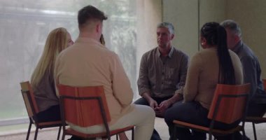 Grup terapisi sırasında başları eğik bir şekilde sessizce oturan adam diğerlerinin sessizce izlediği gibi, sakin ve düşünceli bir şekilde çemberin içinde toplandı.