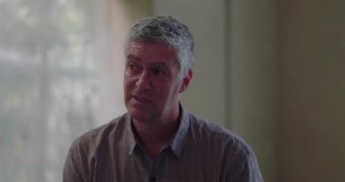 Grup terapi seansı sırasında derin duygular ifade eden bir adamın sessiz ve destekleyici iç mekanda açılırken gözleri kıpkırmızı olur.