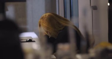 Hüsrana uğramış iş kadını elleri yüzü önünde oturmuş, ofis toplantısı talep ettikten sonra yoğun stresi yönetmeye çalışıyor.