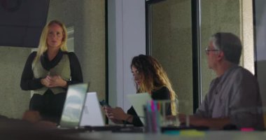 İş arkadaşları cihazları incelerken ve modern takım toplantısı sırasında ofis konferansında notlar alırken sarışın iş kadını sunum yapıyor.